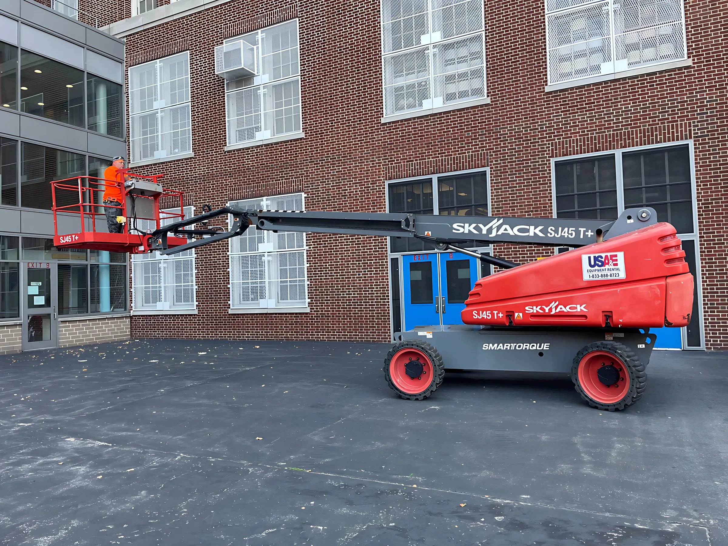 Installer in a boom lift replacing upper-floor windows on a brick school