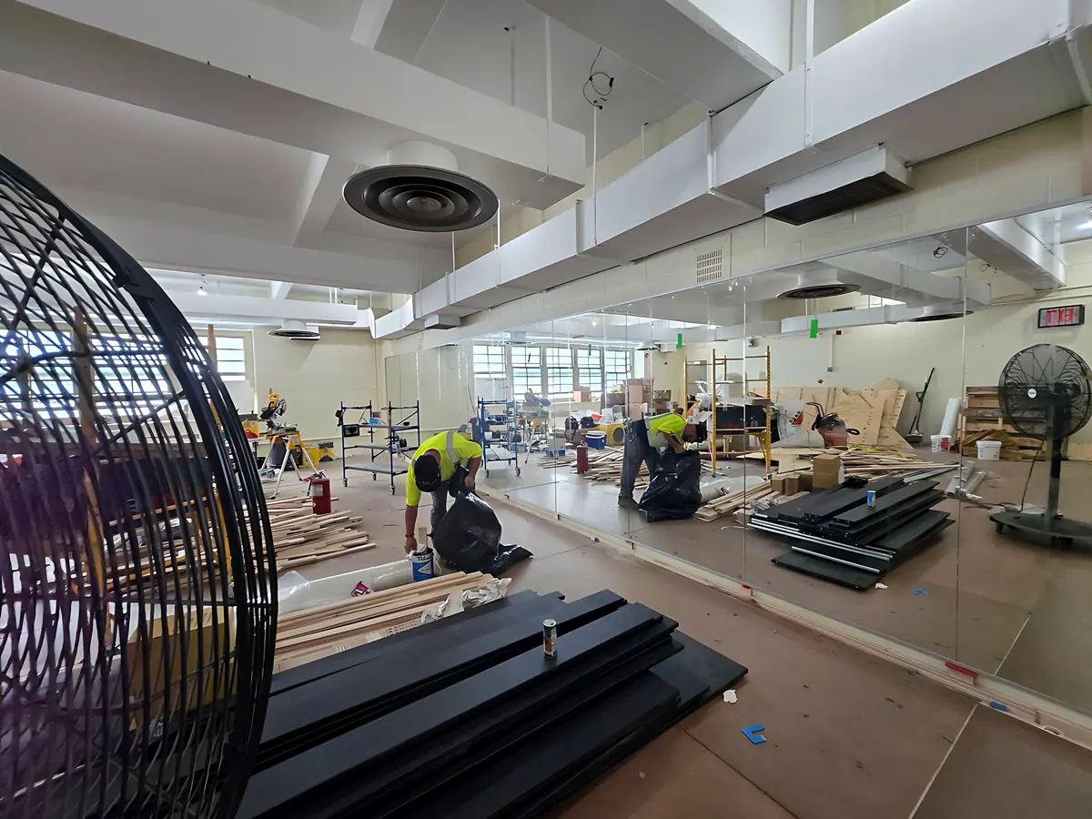 Crew installing a full wall of mirrors in a school gym
