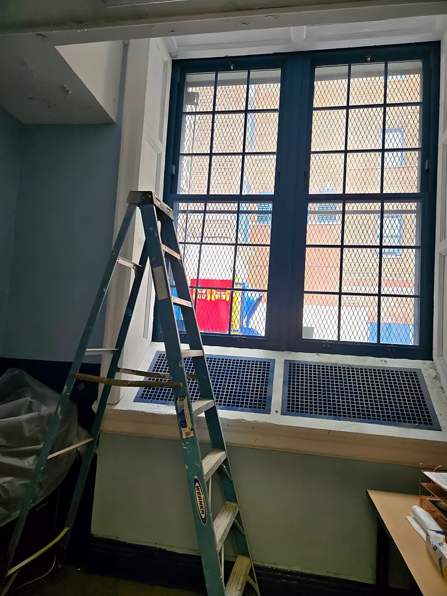 Dark steel window with divided lites in a school classroom, mid-replacement