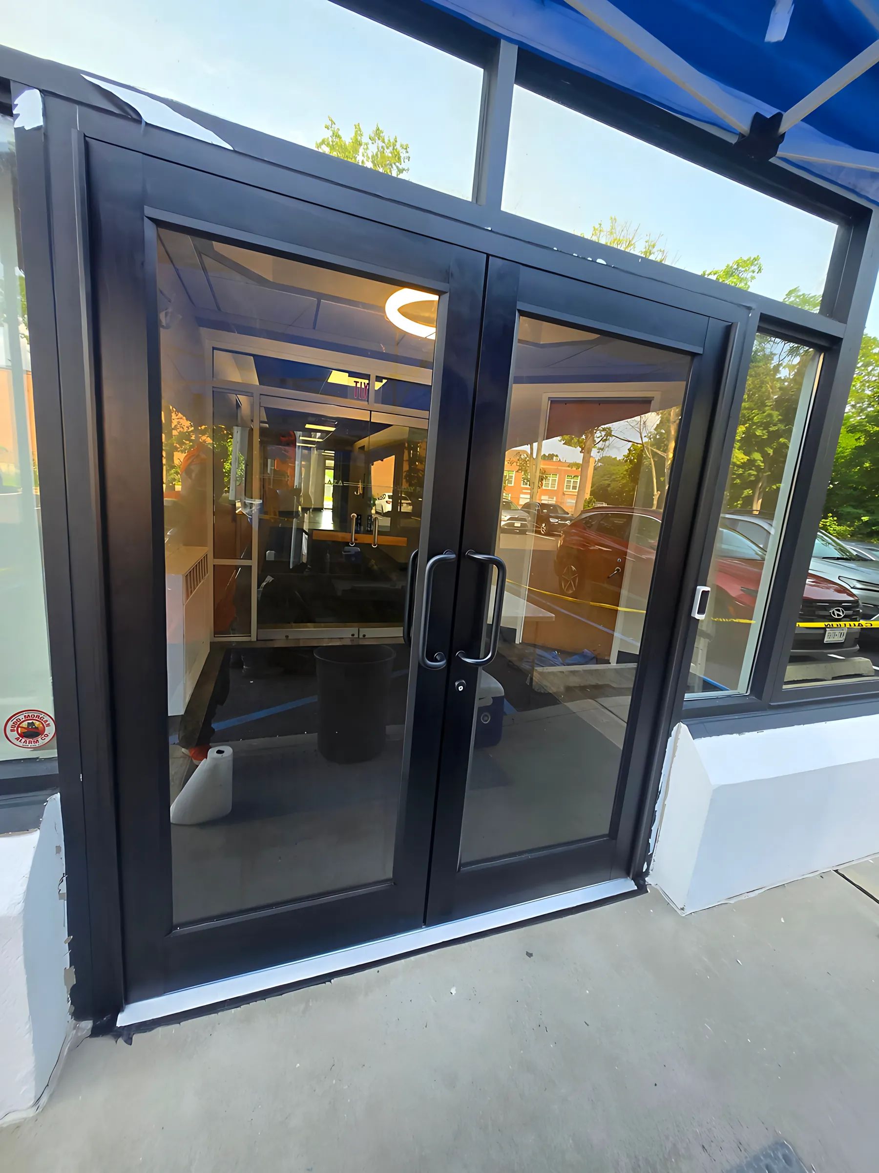 Black aluminum storefront entrance with a pair of glass doors, just installed